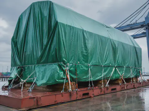 Green tarpaulin cover protecting cargo in a wet port yard